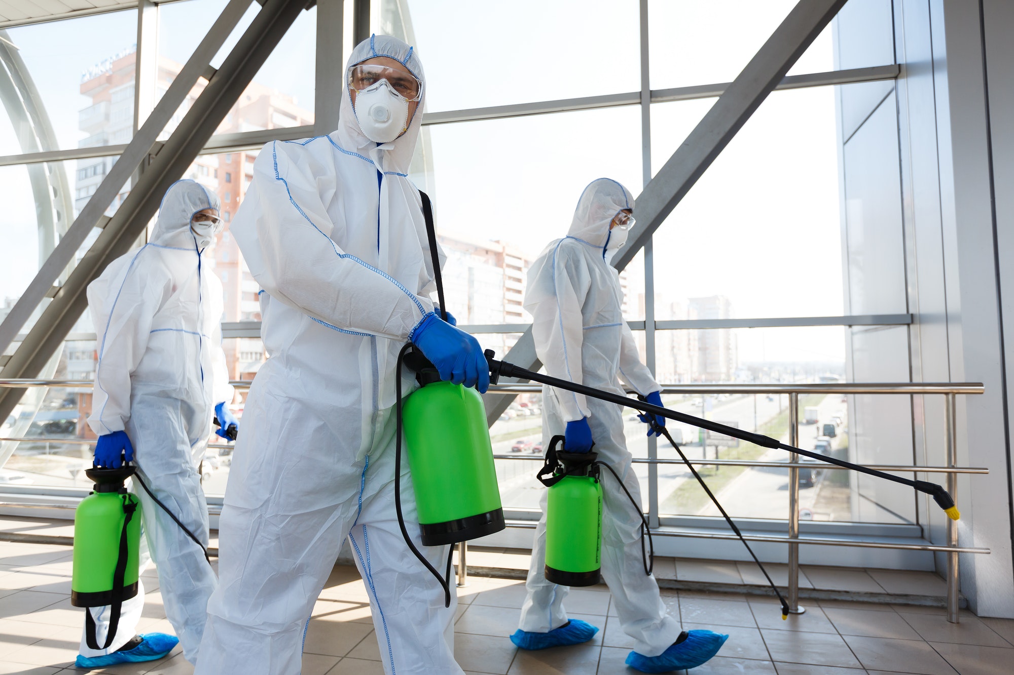 Professional workers in hazmat suits disinfecting indoor accommodation